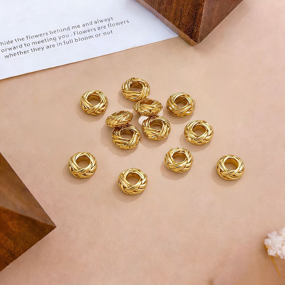 Gold-tone twisted bird's nest beads arranged on a beige surface