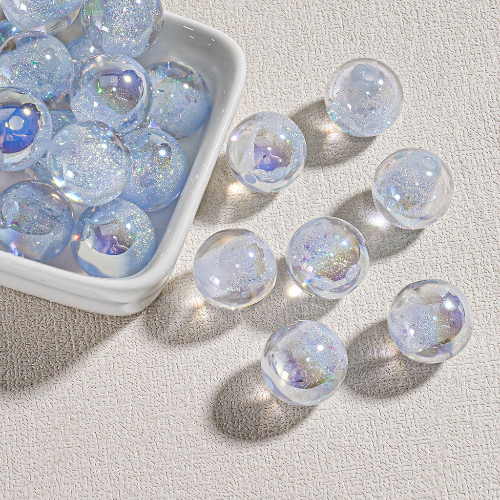 Clear round candy-core opal-effect resin beads with iridescent glitter in white dish on textured surface