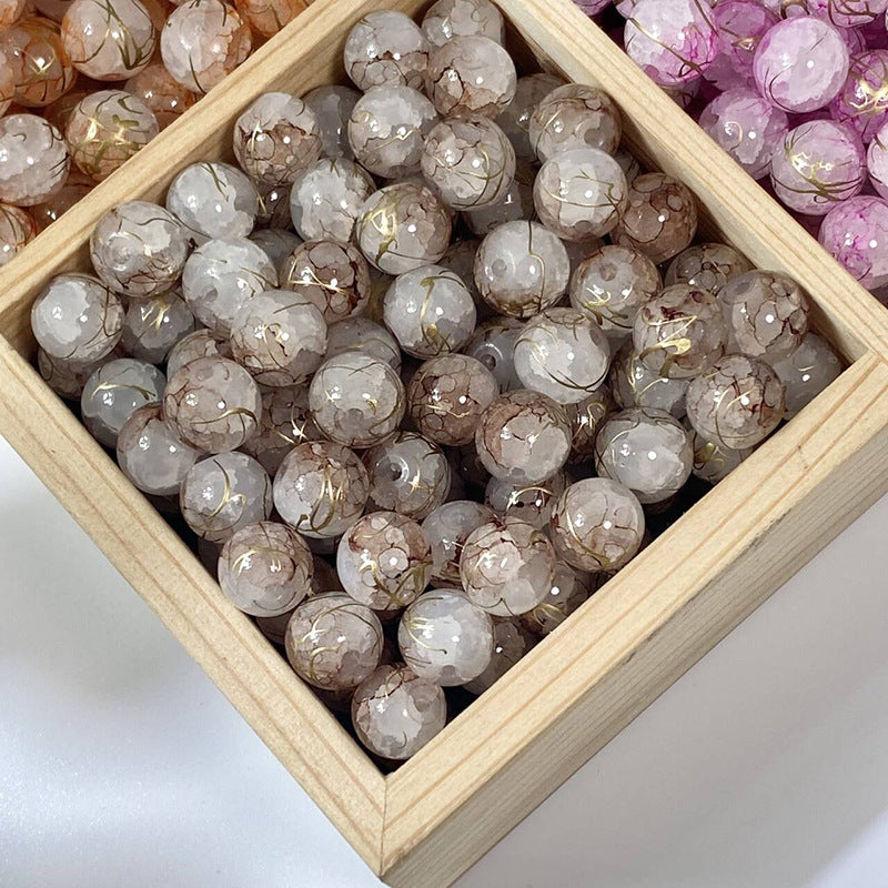 Gray crackle glass beads with gold-silk veins in a wooden tray