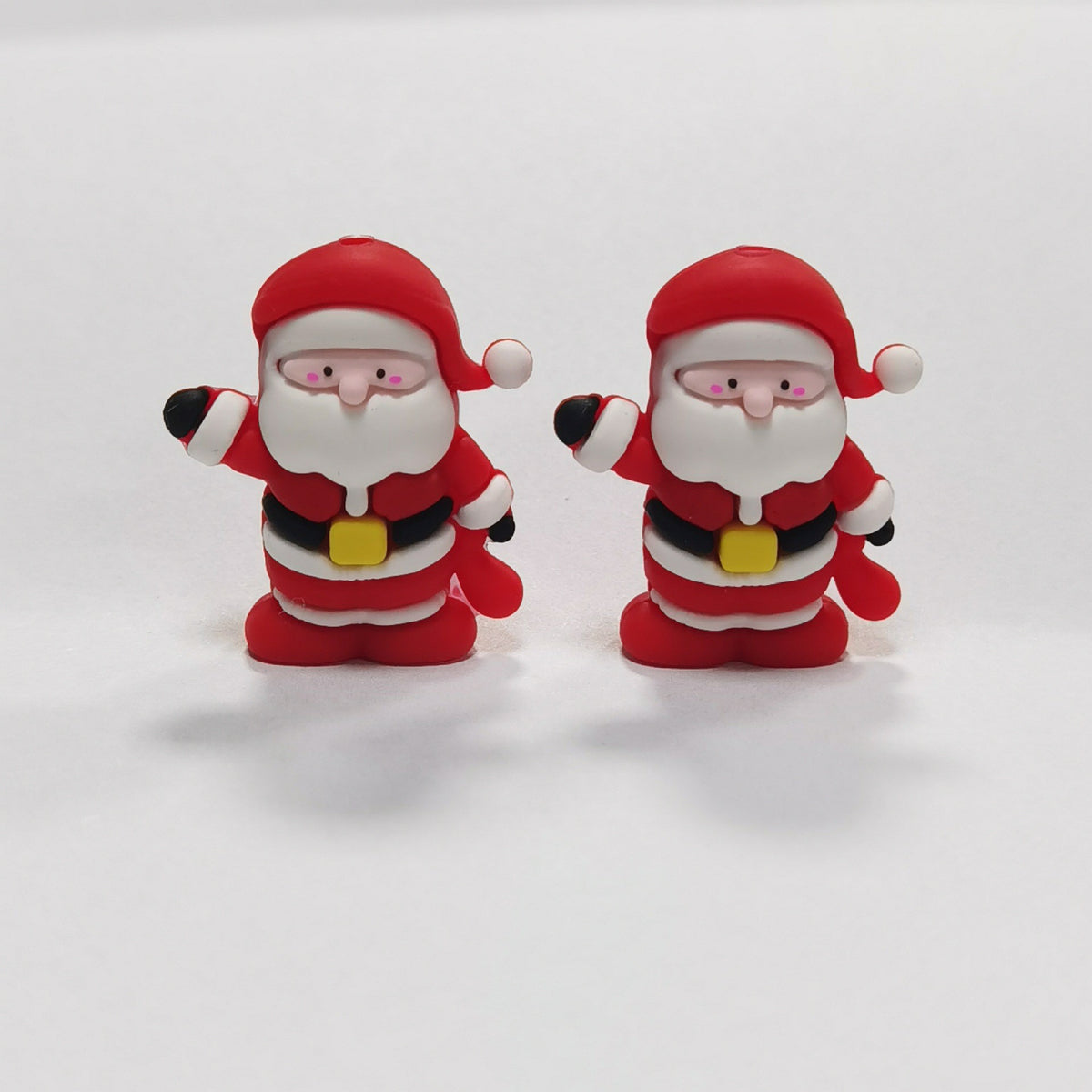 Two Santa Claus silicone focal beads in red suits with white beards and yellow belt buckles