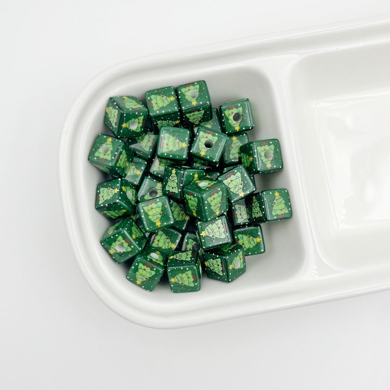 Pile of green square beads with Christmas tree prints in a white divided tray