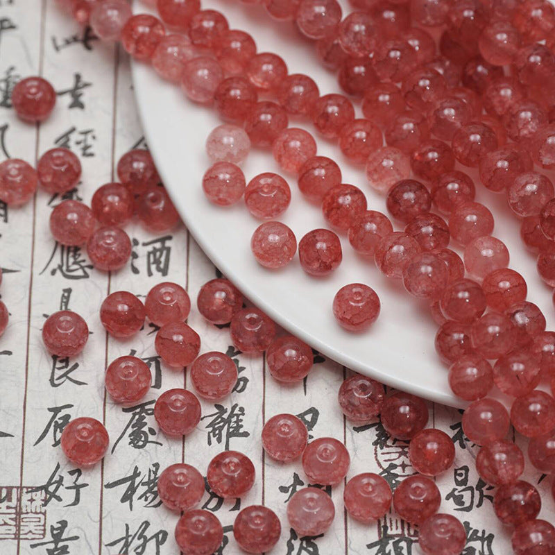 Red ice-crackle glass beads spilling from a white plate onto calligraphy paper