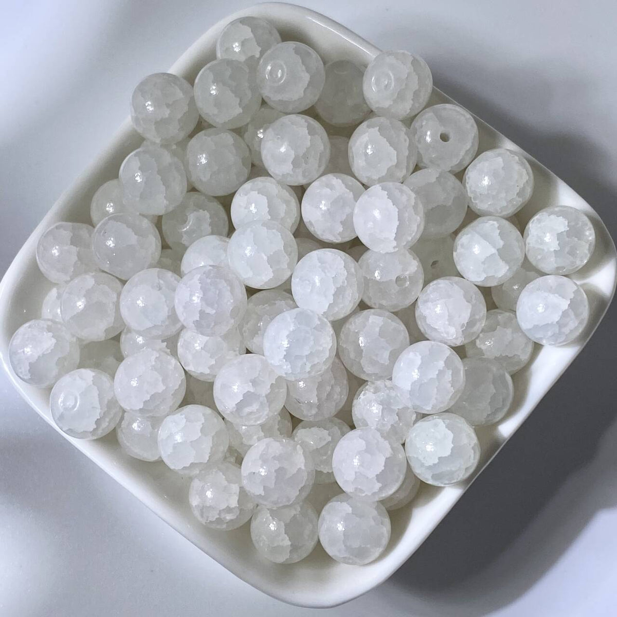White 10mm water-dyed jade-style crackle glass beads in a white square dish