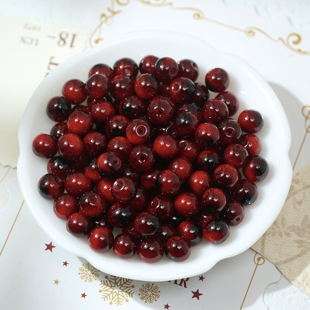 Round glossy red tiger's eye glass beads in a white bowl
