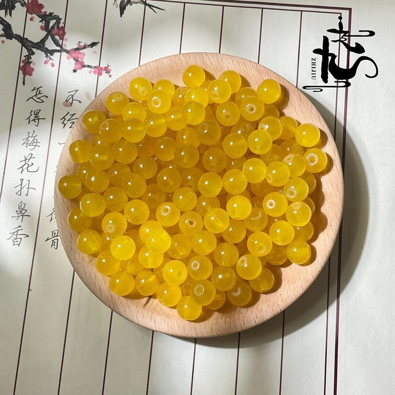 Yellow translucent round beads filling a wooden bowl with calligraphy background