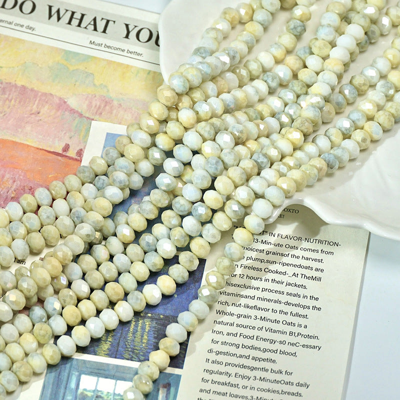 Multiple strands of light green and cream faceted porcelain beads on printed pages