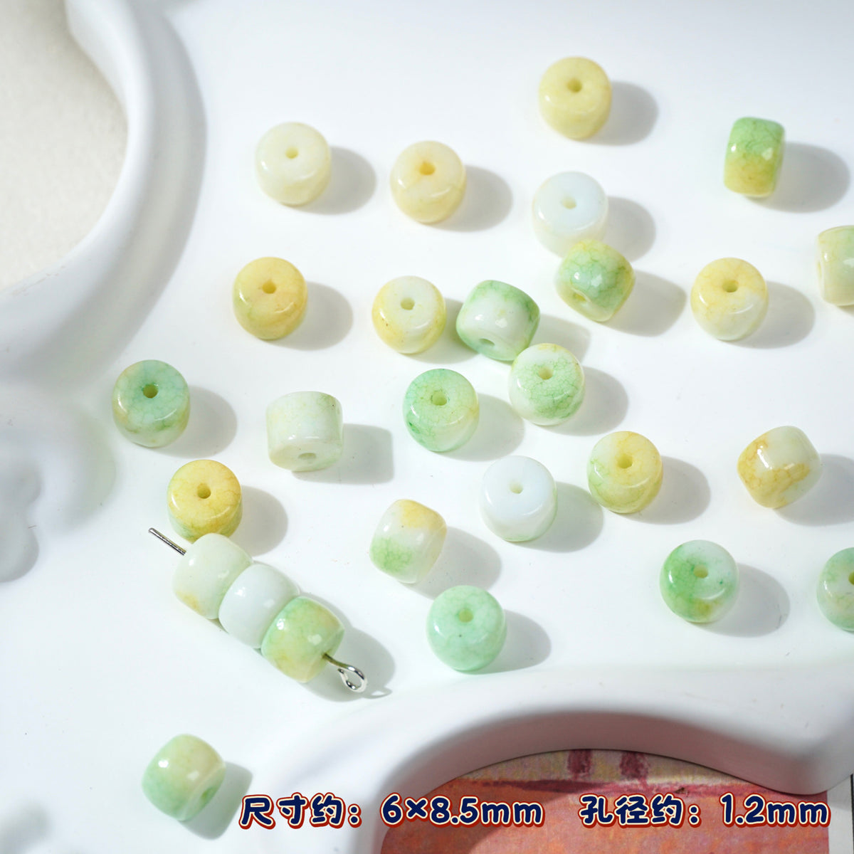 Small cylindrical porcelain beads in pale yellow, mint green, white on white