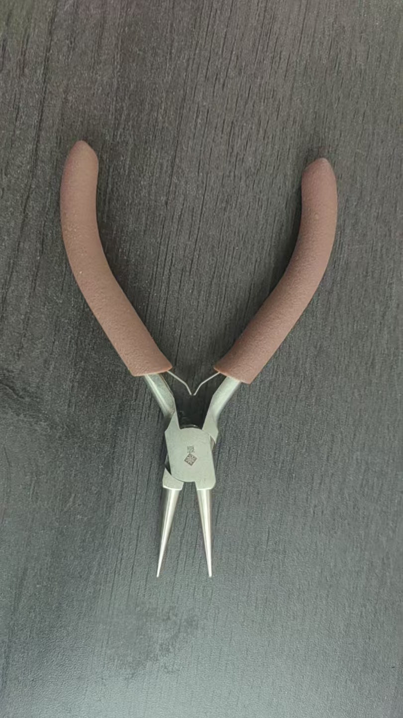 Brown-handled round-nose pliers with silver jaws on dark gray