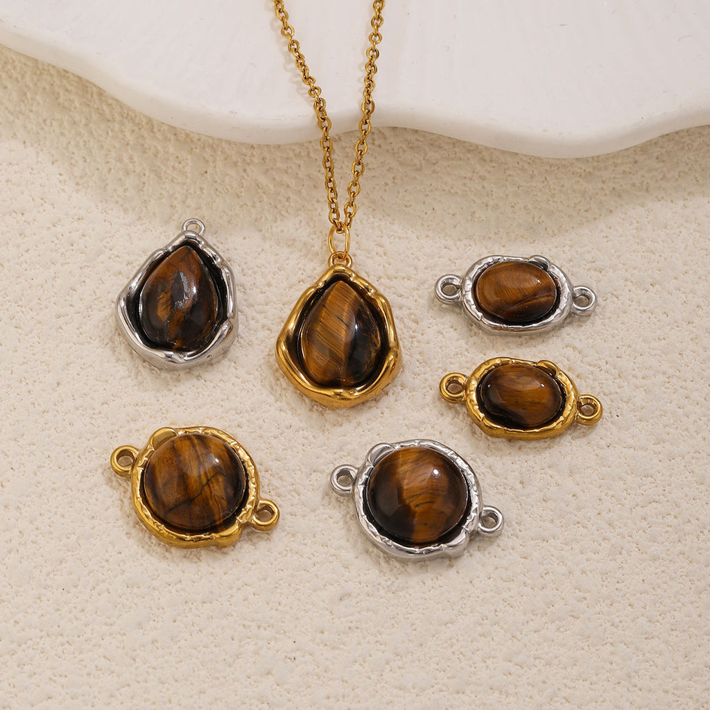 Six tiger's eye charms: two teardrop pendants and four oval double-hole connectors, gold and silver bezels, on beige surface