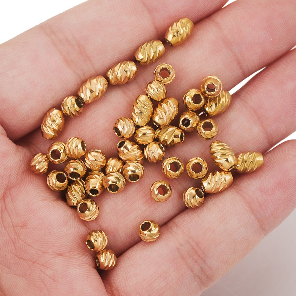 Hand holding gold-plated diamond-cut stainless steel wheel spacer beads