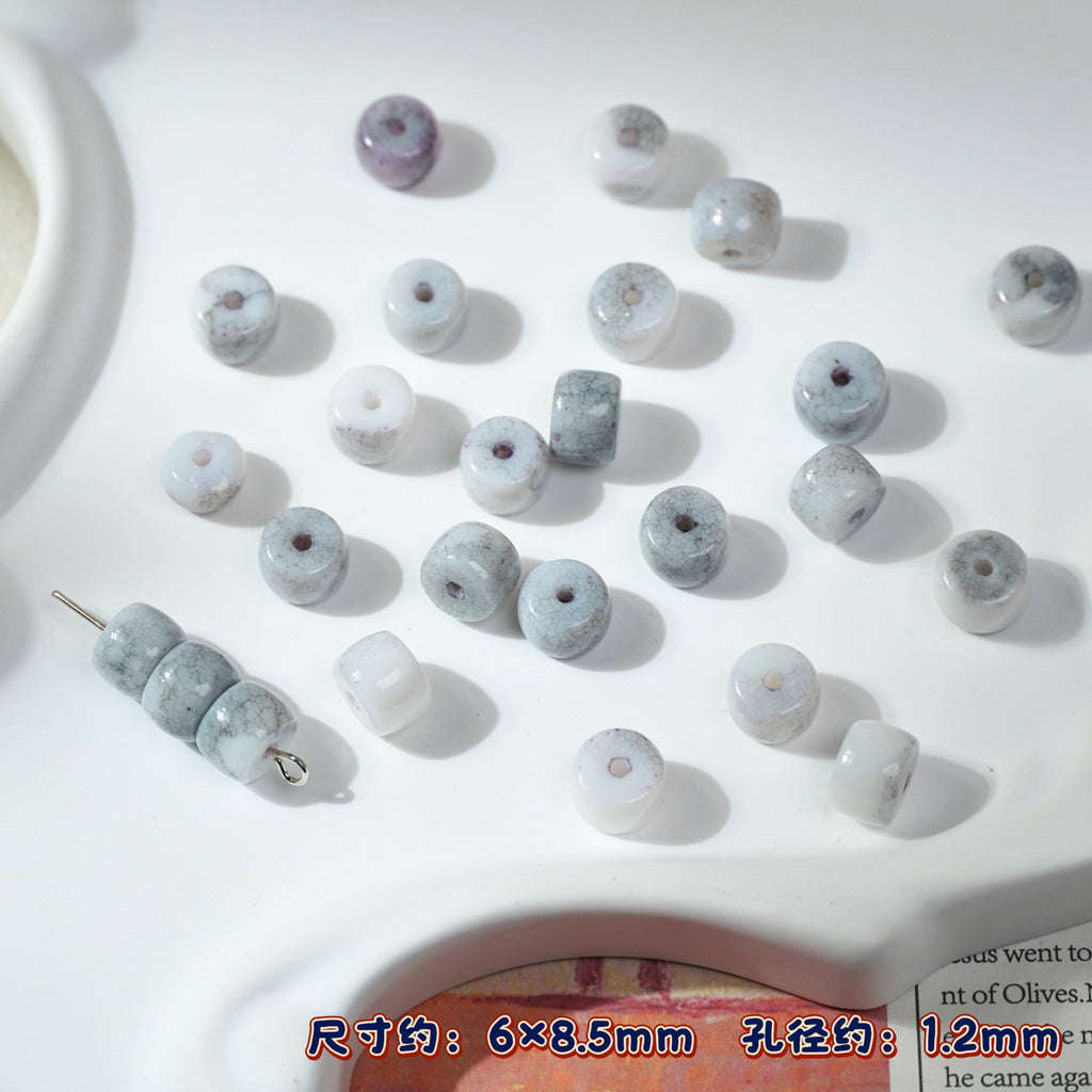 Small round porcelain beads in gray, white, purple on white surface