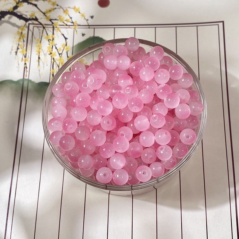 Translucent pink glass beads in a clear round bowl photographed from above
