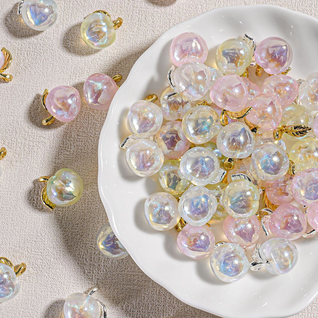 White plate of round iridescent mini peach beads with gold-tone loops, plus a few scattered beads