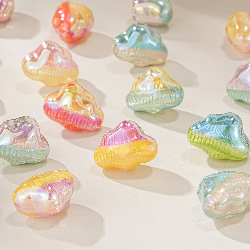Iridescent cloud-shaped resin beads in pink, yellow, blue, green, and orange scattered on a light beige surface.