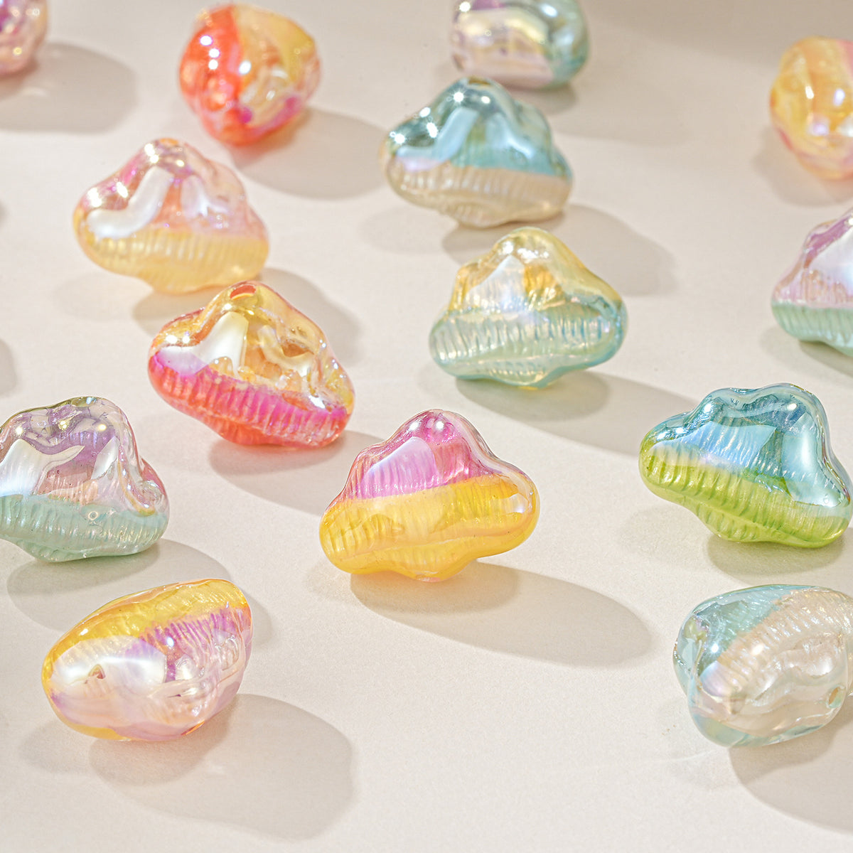 Iridescent cloud-shaped resin beads in pink, yellow, blue, green, and orange scattered on a light beige surface.
