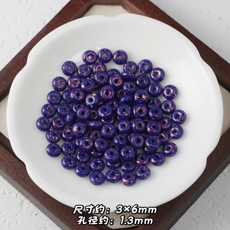 Deep blue Picasso glass abacus beads with copper speckles piled in a white scalloped dish.