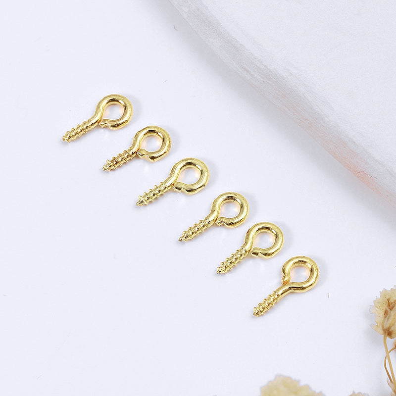 Five gold-colored screw eye pins with threaded shafts arranged diagonally on white