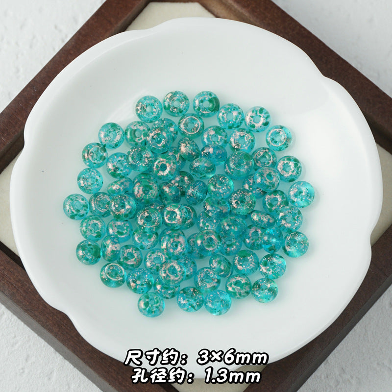 Translucent turquoise Picasso glass abacus beads with white speckles piled in a white ceramic dish.