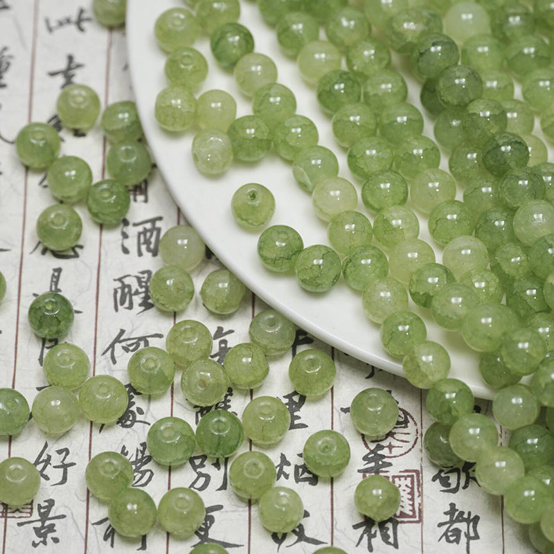 Light green ice-crackle glass beads scattered on calligraphy paper and a white plate
