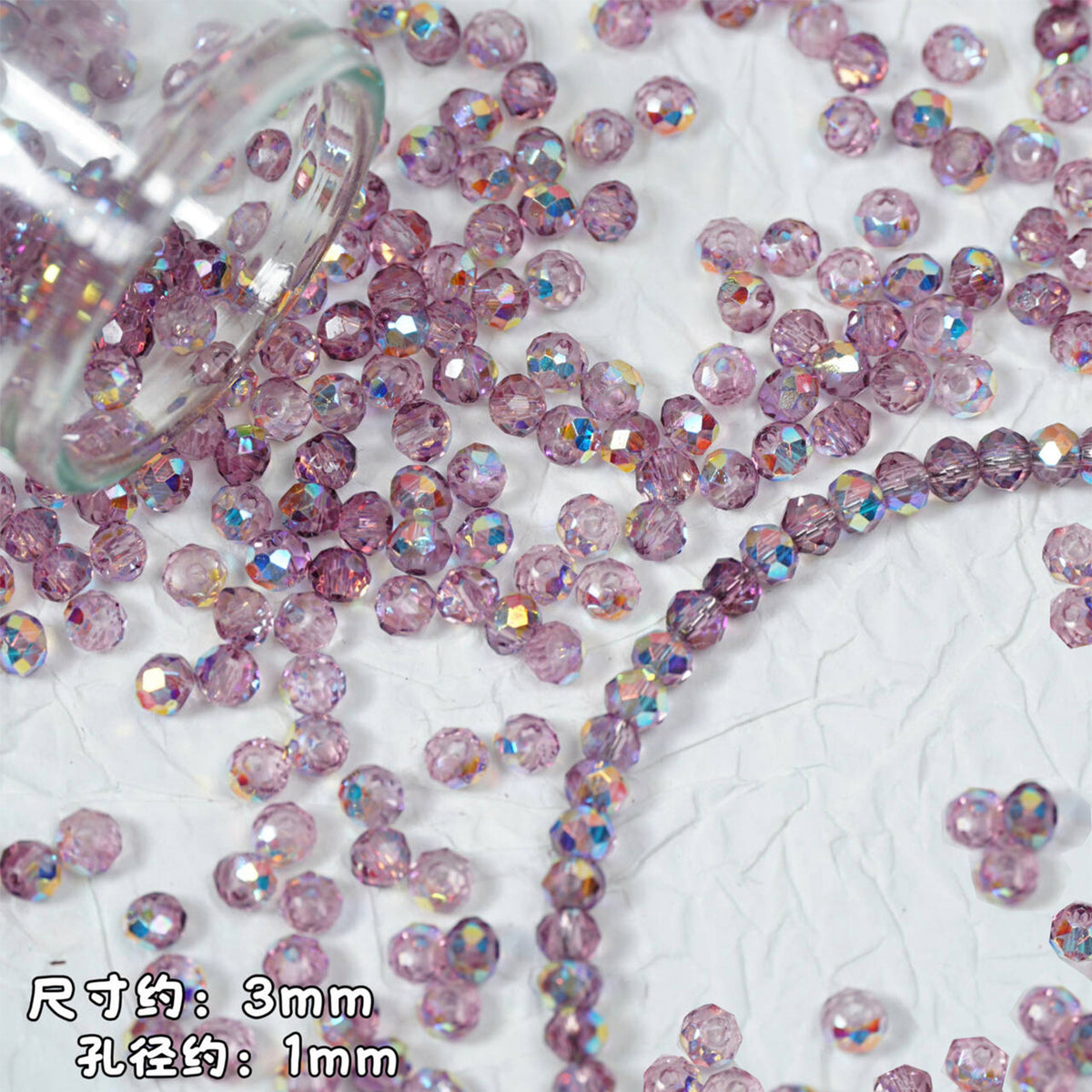 Pink faceted glass beads scattered on a textured white surface, with a clear glass container tipped to release more beads. Chinese text in the bottom-left indicates approximate size: 3mm diameter and 1mm hole size.