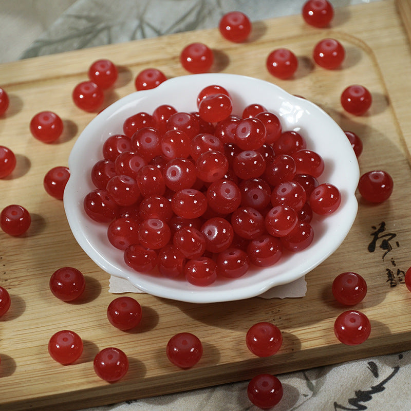 Red translucent round beads in a small white bowl on a wooden cutting board