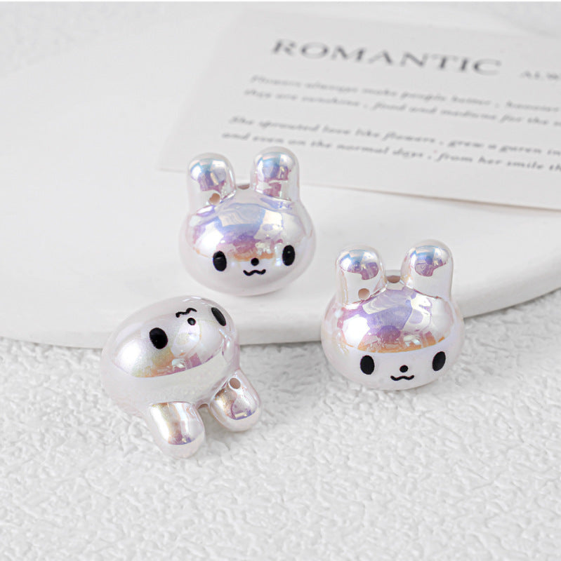 Three iridescent silver bunny-shaped acrylic charms on white textured surface