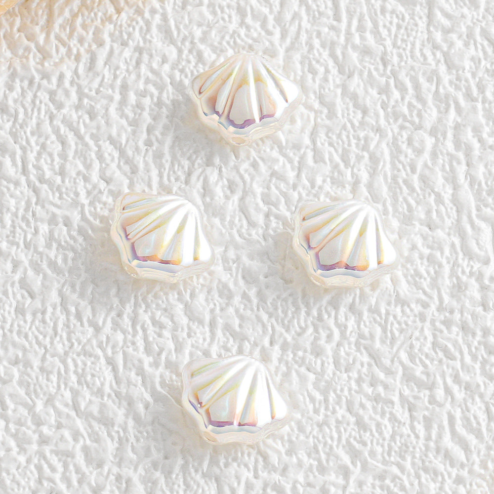 Four iridescent shell-shaped faux pearl beads on a textured white surface