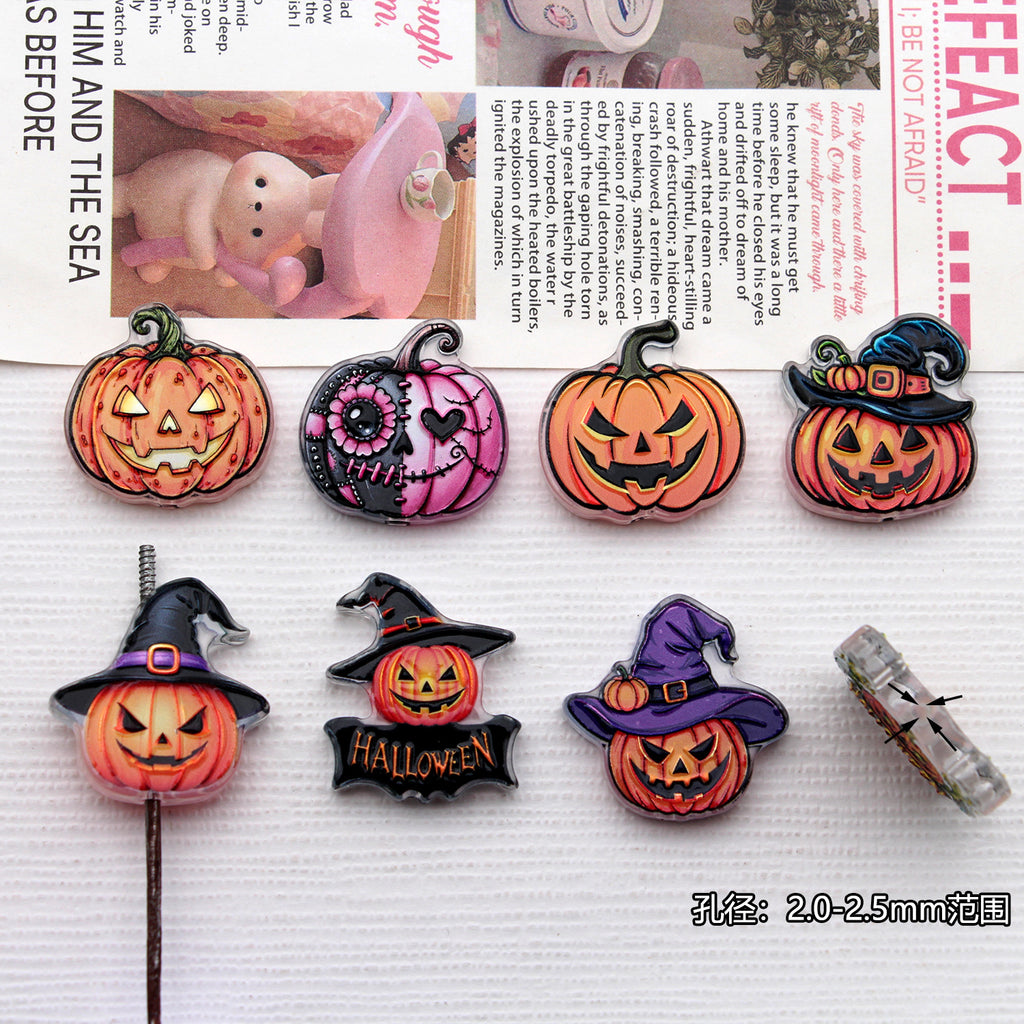 Seven Halloween acrylic pumpkin charms with witch hats and jack-o'-lantern faces on a white textured surface