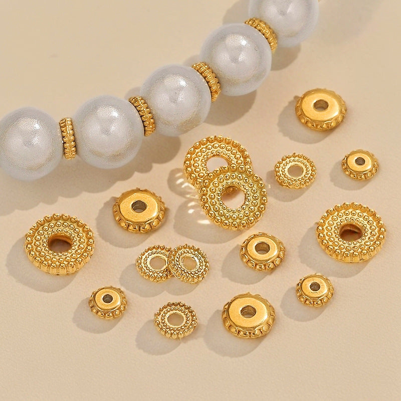 Gold-plated dotted gear wheel stainless steel spacer beads with pearl beads on beige background