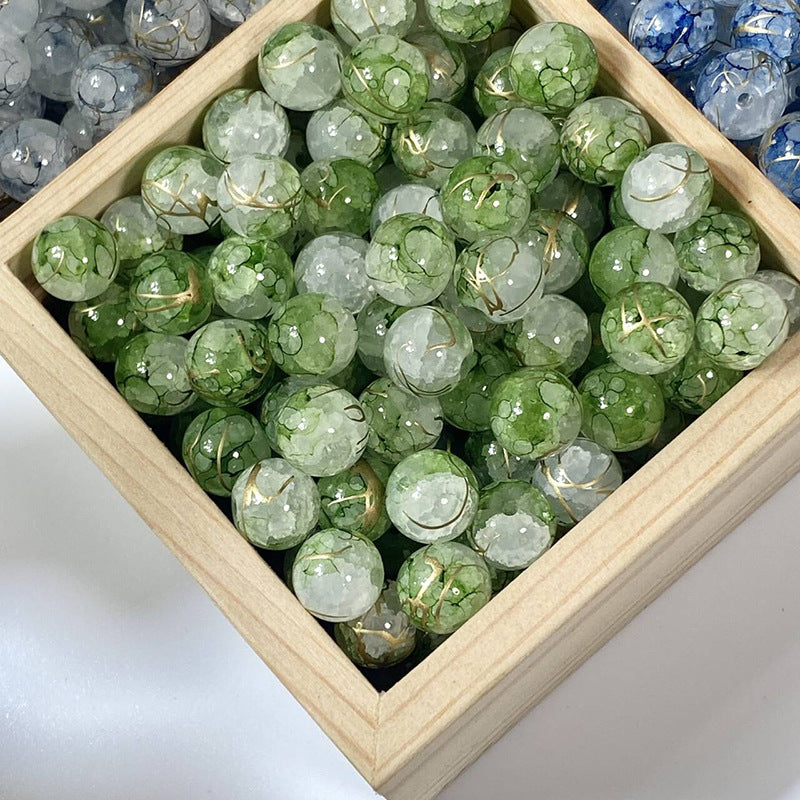 Green crackle glass beads with gold-silk veins in a wooden tray