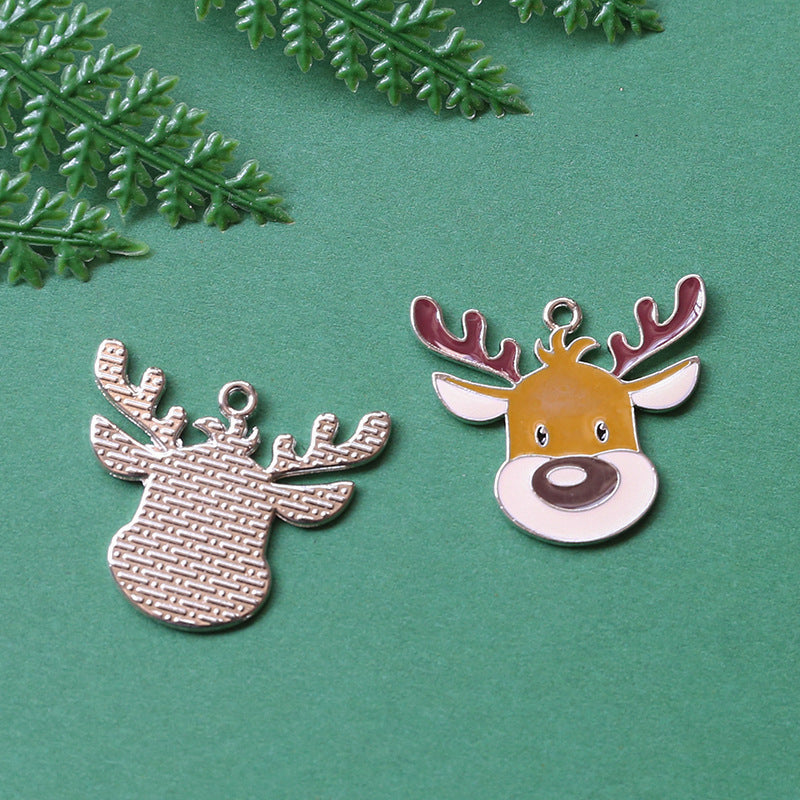 Two Christmas-themed deer charms on textured green background with pine needles