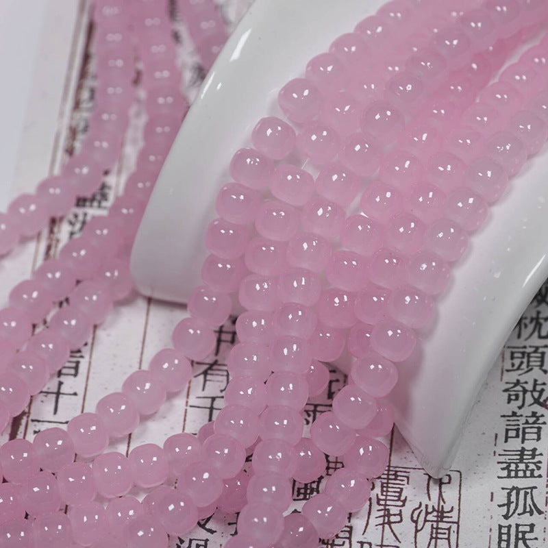 Pink translucent round bead strands draped over a white ceramic stand on printed paper with Chinese characters