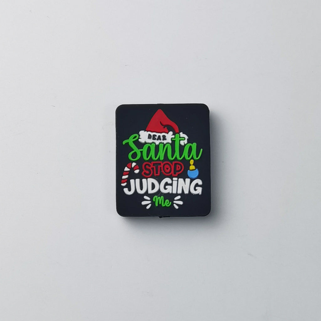 Square black silicone focal bead with 'Dear Santa STOP JUDGING Me' text in green, red and white, small red Santa hat