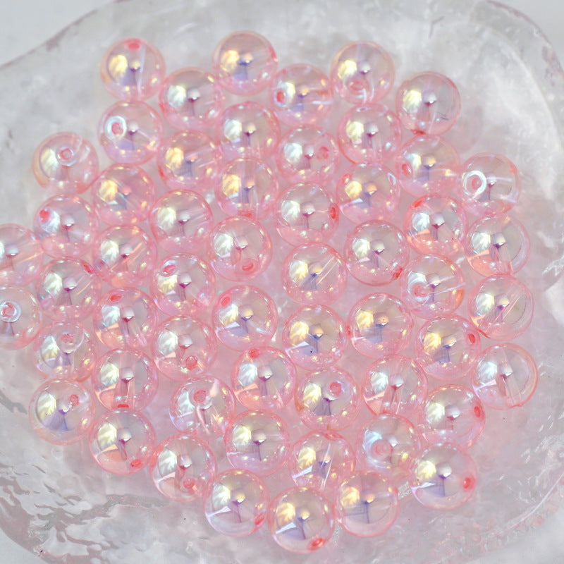 A pile of round, iridescent pink beads with a glossy finish, arranged in a clear glass dish.