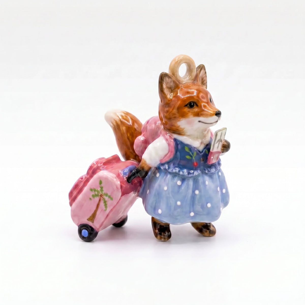 3D fox pendant charm in blue polka-dot dress and pink backpack, pulling pink suitcase.
