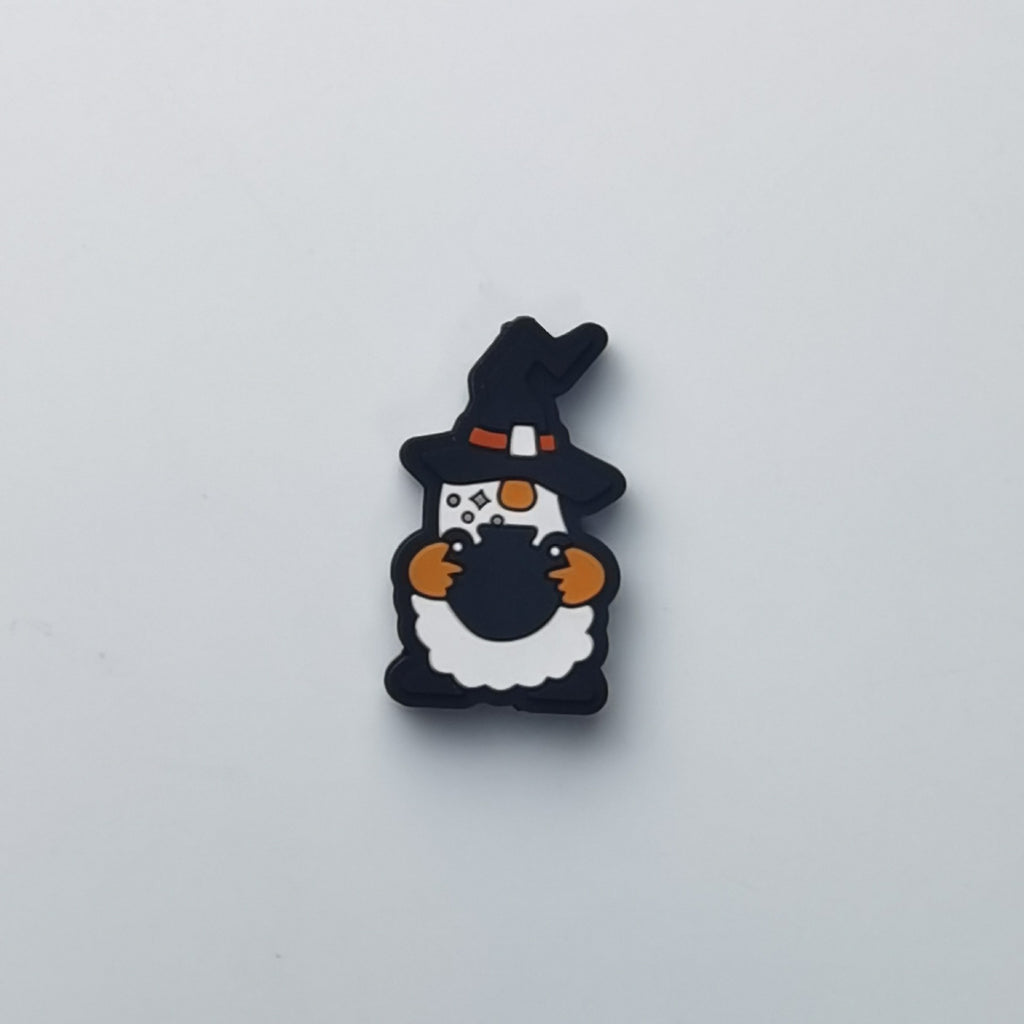 A small cartoon gnome charm or accessory in black, white, and orange, centered on a plain light gray background.