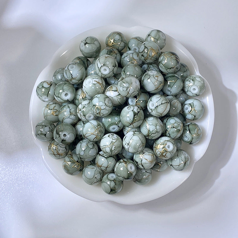 White bowl of marbled gray-green glass beads with gold-silk veining