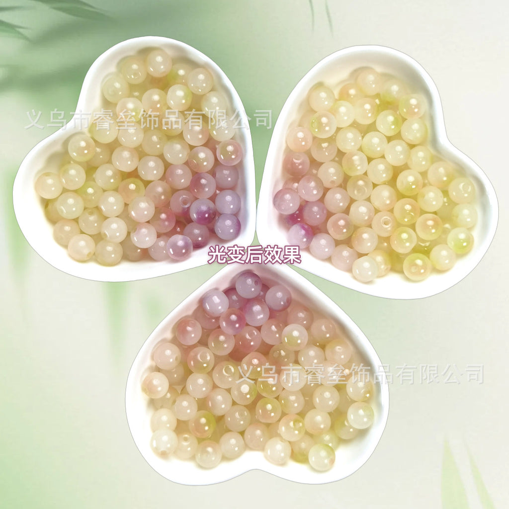 Three heart-shaped bowls of pastel cream, yellow, pink, and lavender beads on pale green