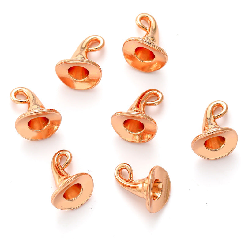 Several rose gold metal witch hat charms on a white background.