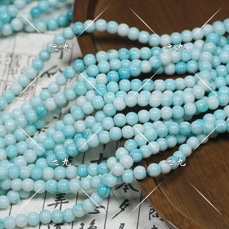 Multiple strands of light blue and white round porcelain beads on wooden surface
