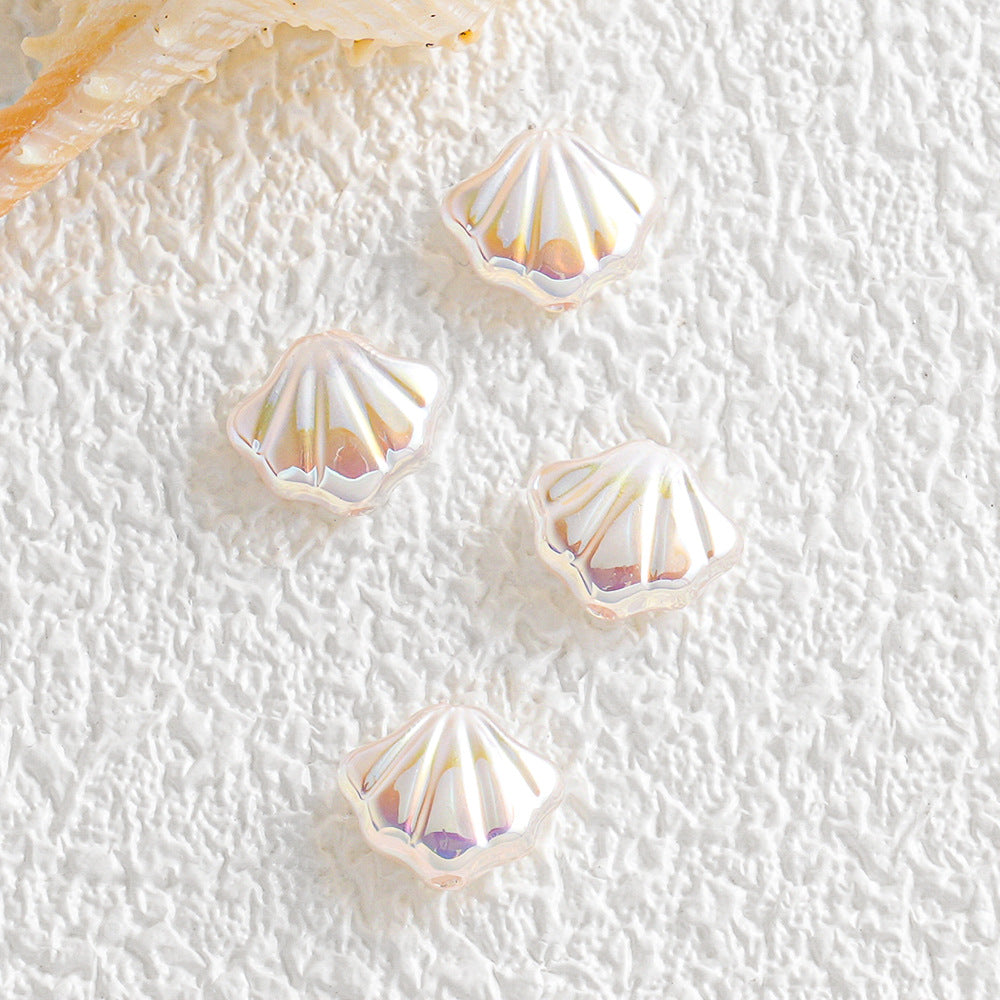 Four small iridescent shell-shaped beads on a textured white surface