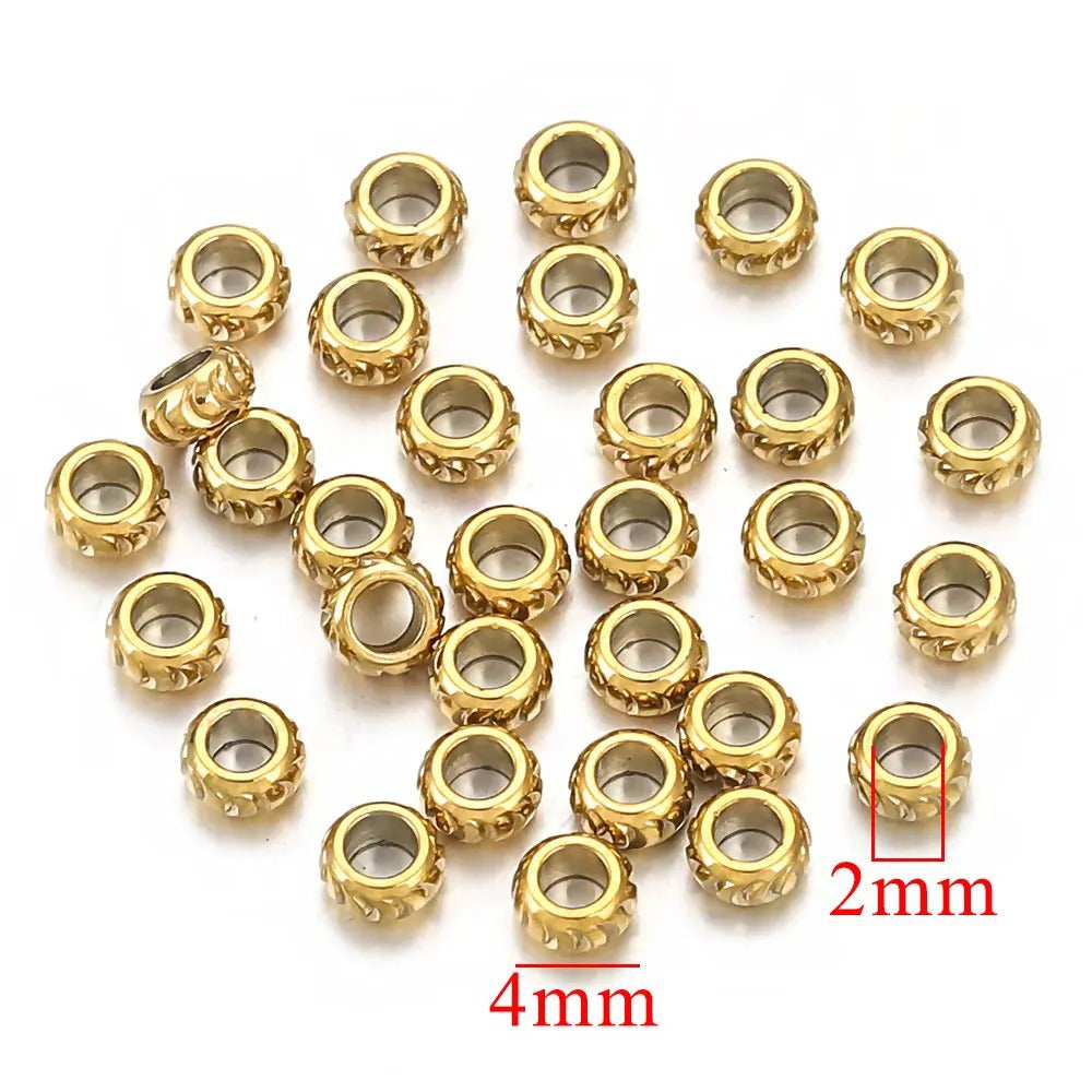 Pile of small gold-plated diamond-cut stainless steel abacus spacer beads with hollow centers