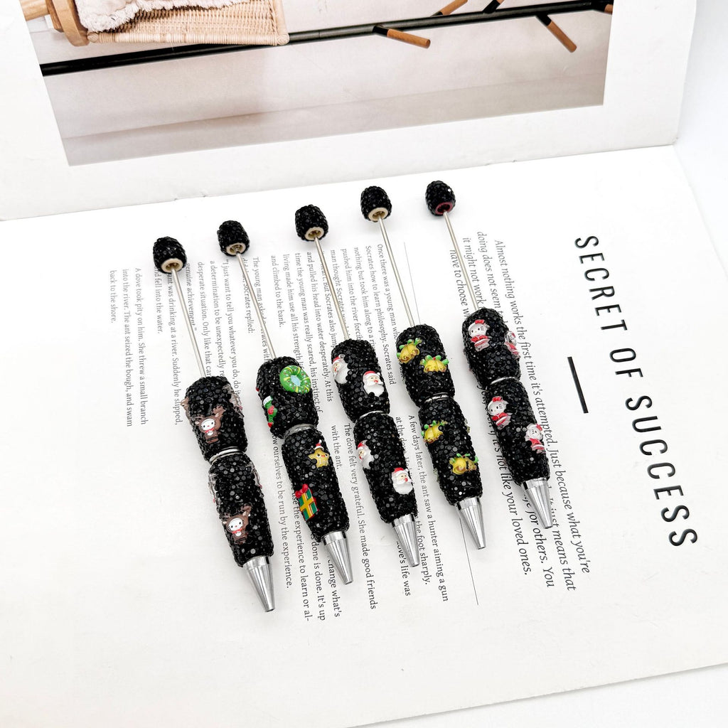 Five black rhinestone ballpoint pens with colorful cartoon designs.