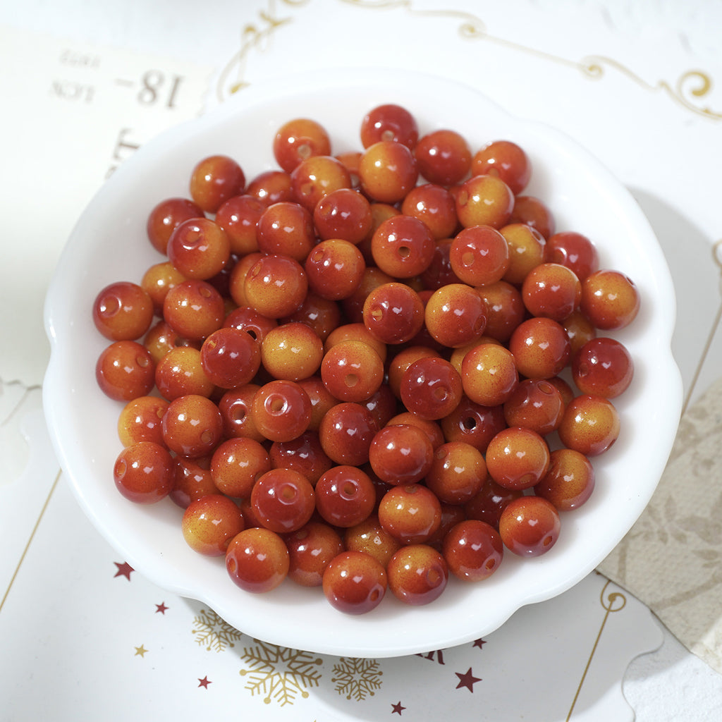 Glossy round red-orange glass beads in a white bowl
