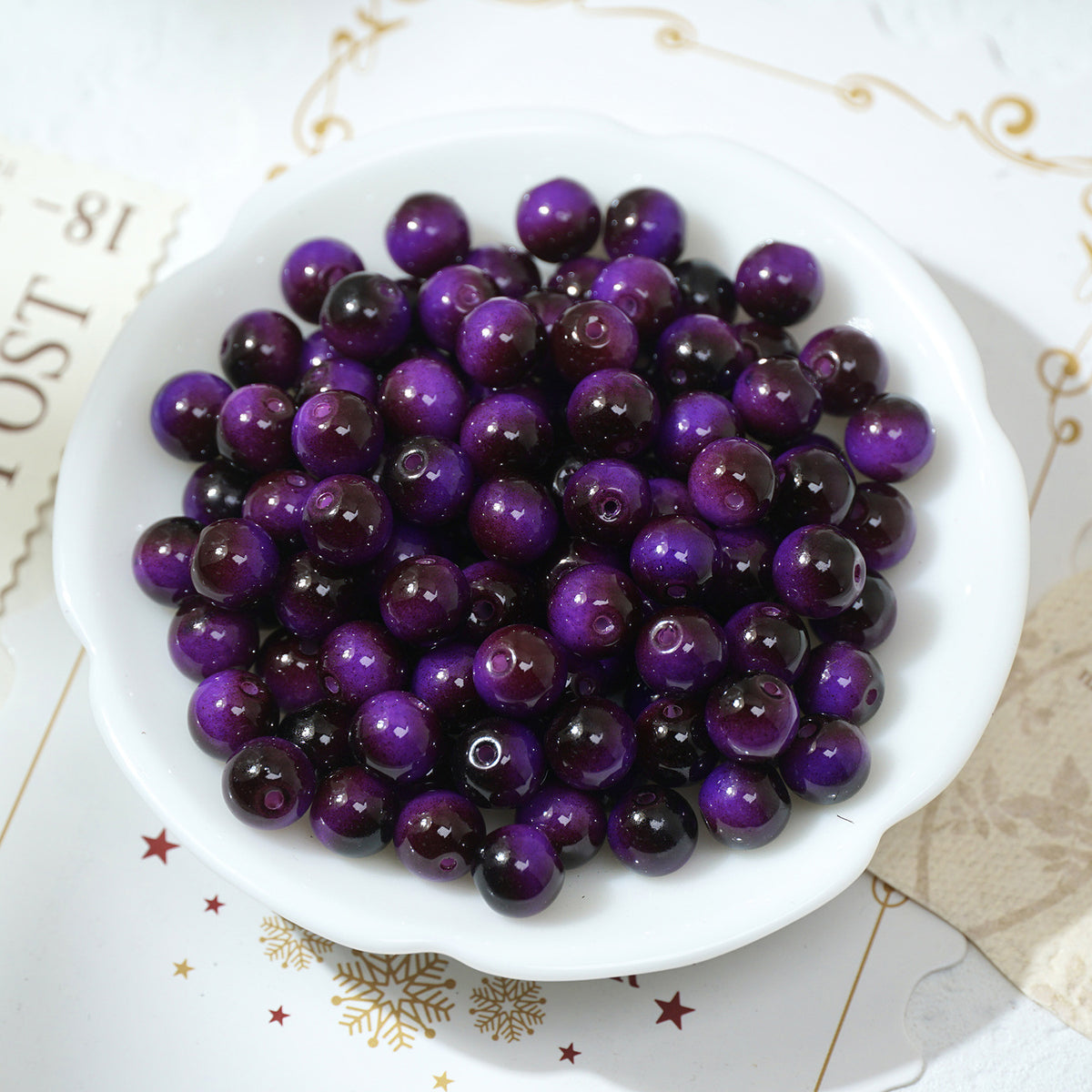 Glossy purple and dark purple round glass beads in a white scalloped dish