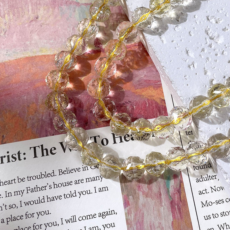 Clear faceted glass beads threaded on a thin gold string arranged diagonally across a printed book page