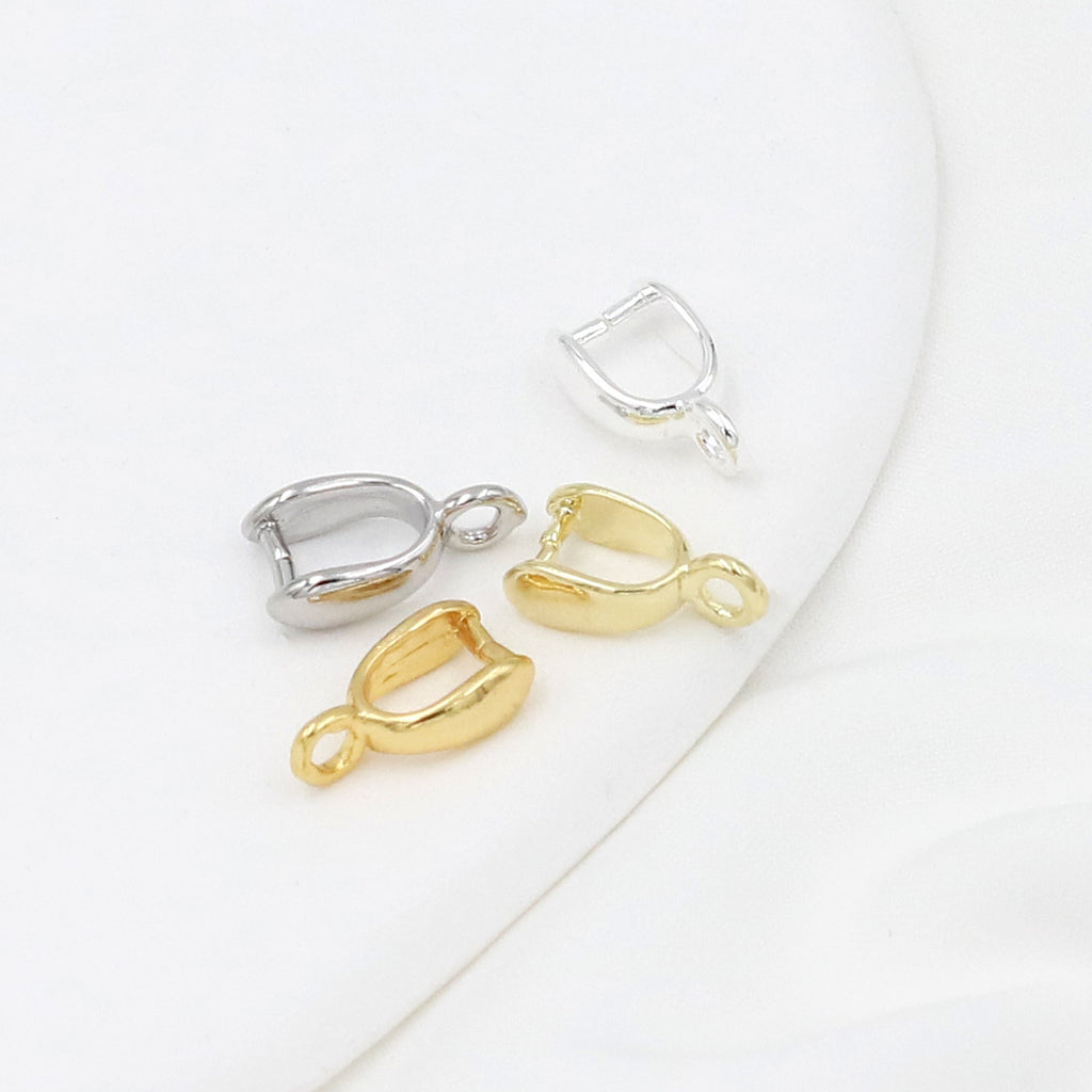 Four small gold-plated pinch bail pendant clasps in gold and silver finishes on a white curved surface