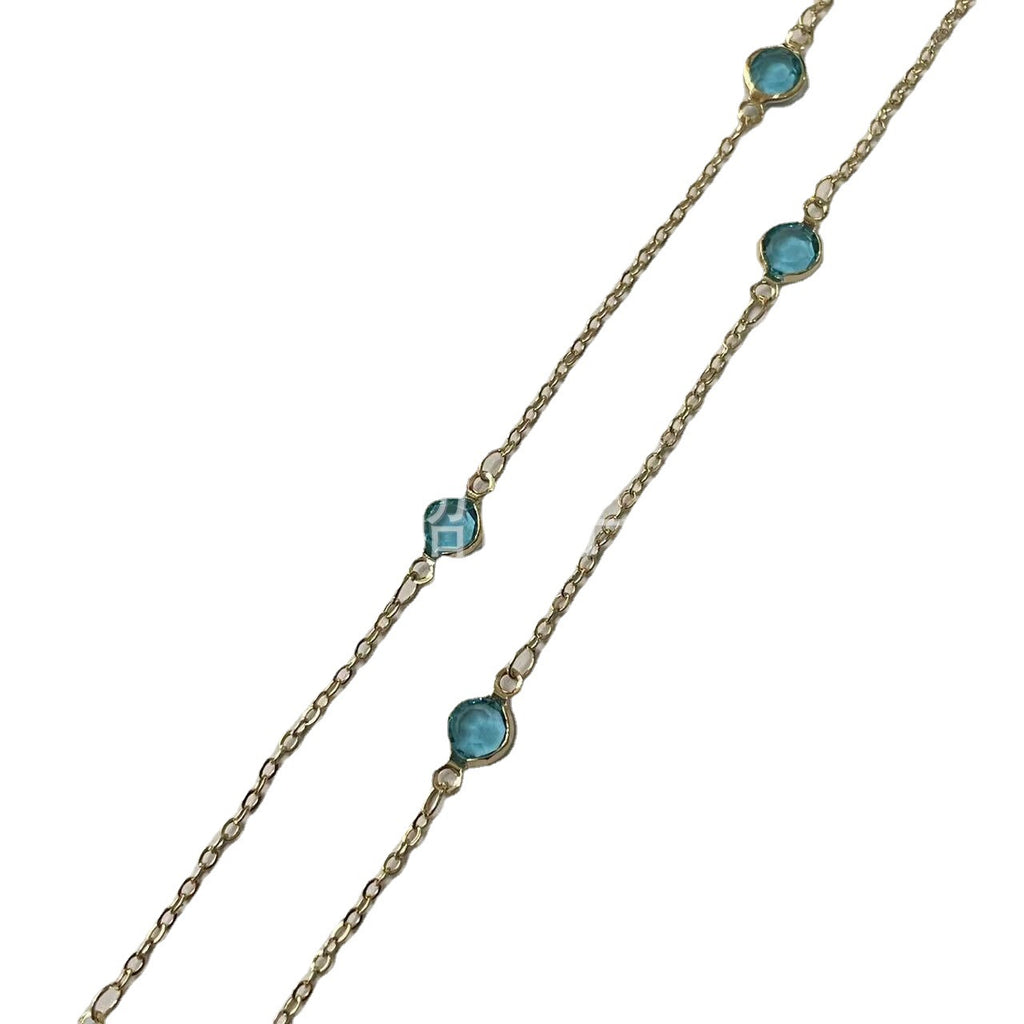 Gold chain necklace with three light blue faceted gemstones of different shapes