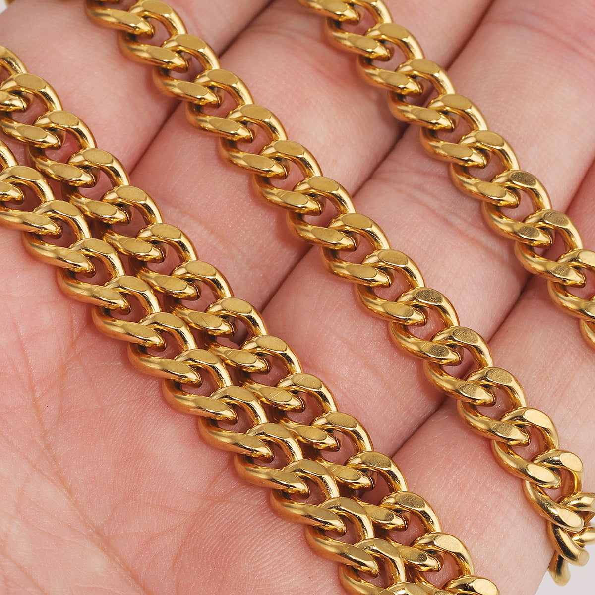 Close-up of gold-plated NK Cuban curb chain links draped across a person's hand