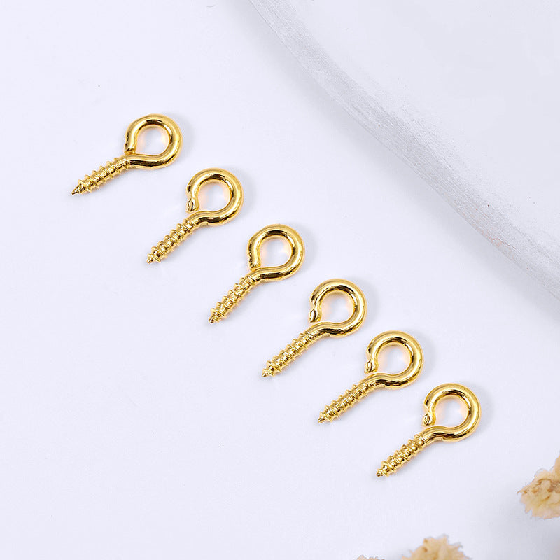 Five small gold-colored screw eye pins arranged diagonally on a white background